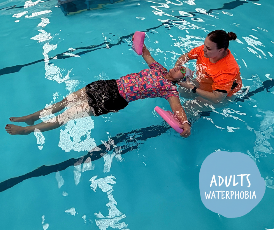 Swimming instructor leading children in a pool exercise, all wearing swim caps.