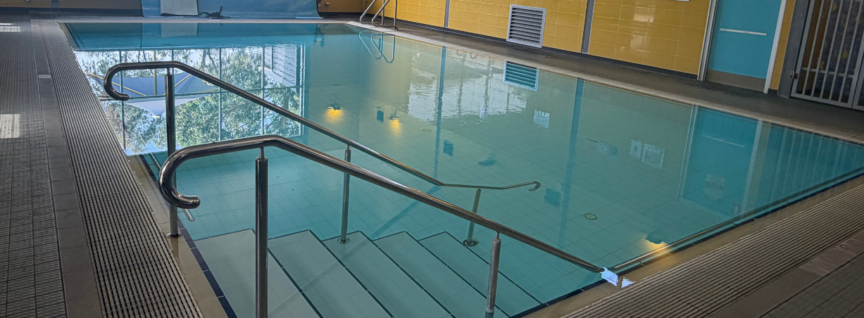 Indoor swimming pool with bright yellow walls and turquoise water.
