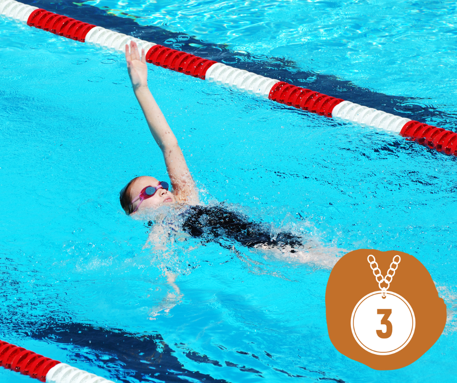 Swimmer in cap and goggles swims breaststroke in a pool with lane markers.