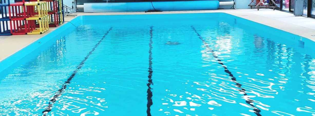 A rectangular swimming pool filled with turquoise water, marked with black lane lines.