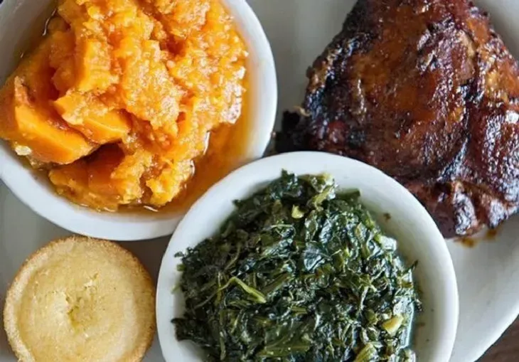 A white plate topped with bowls of food including sweet potatoes , spinach and meat.