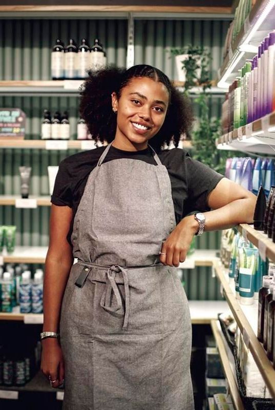 A woman in an apron is standing in a store.