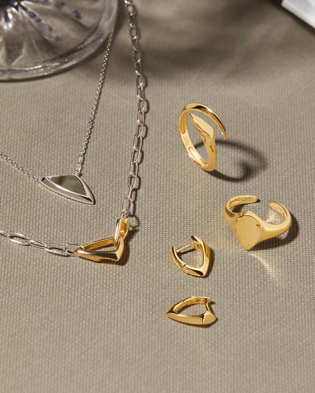 Ensemble de bijoux en or et argent sur une surface satinée. Colliers, bagues et boucles d'oreilles inclus.