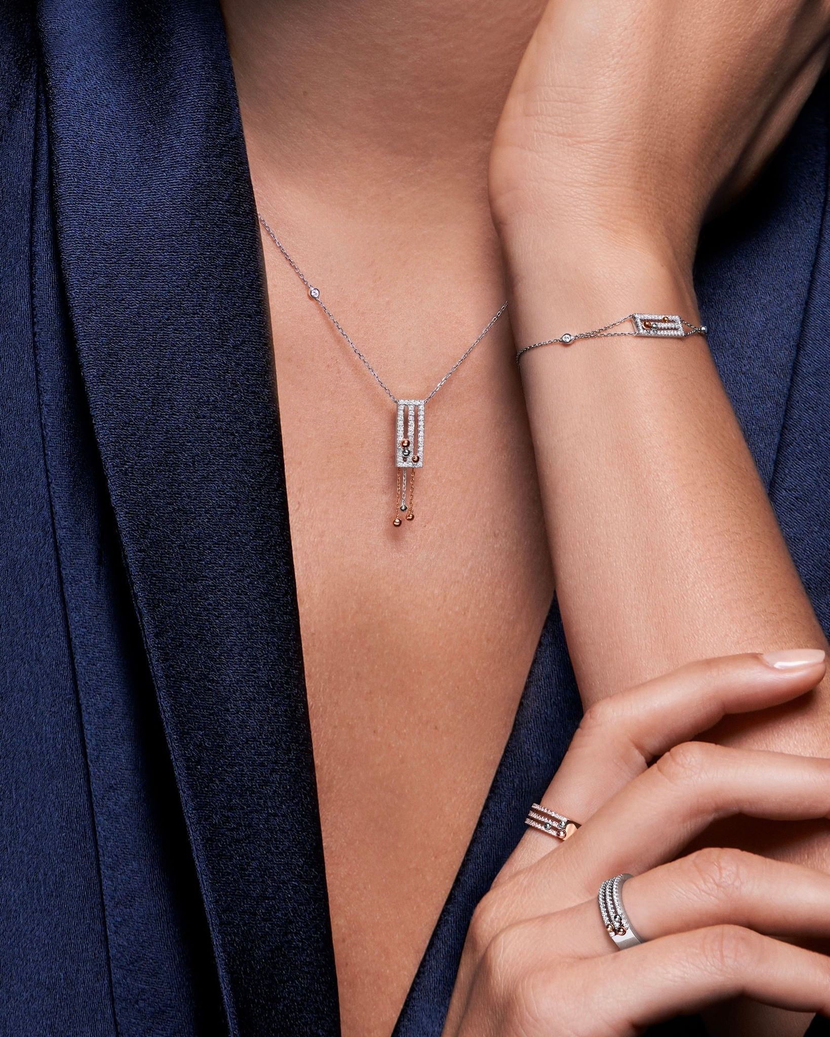 Femme portant des bijoux : collier, bracelet, bague sur veste bleue.