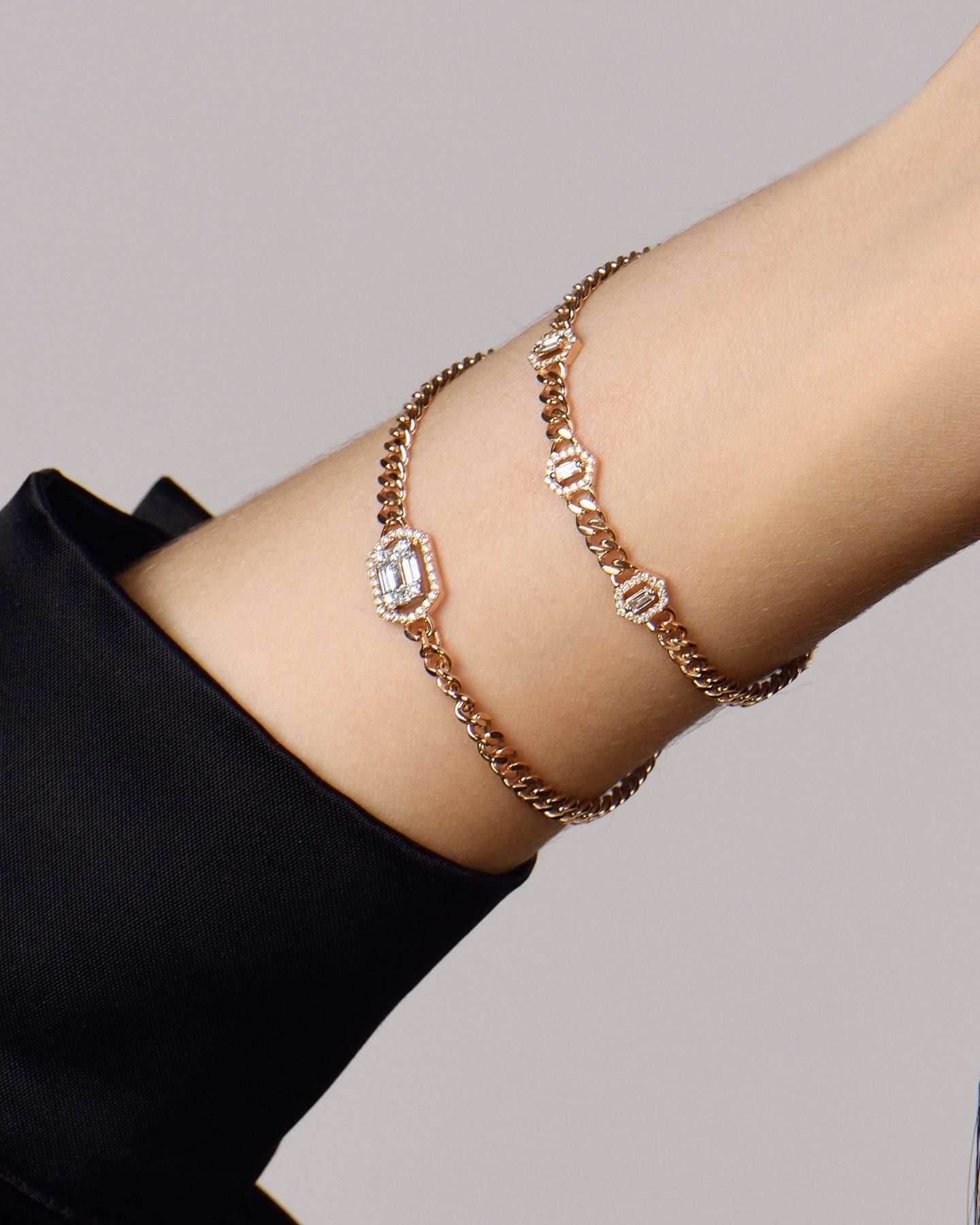 Bracelets en or rose avec des accents de diamants sur un poignet, à côté d'une manche noire.