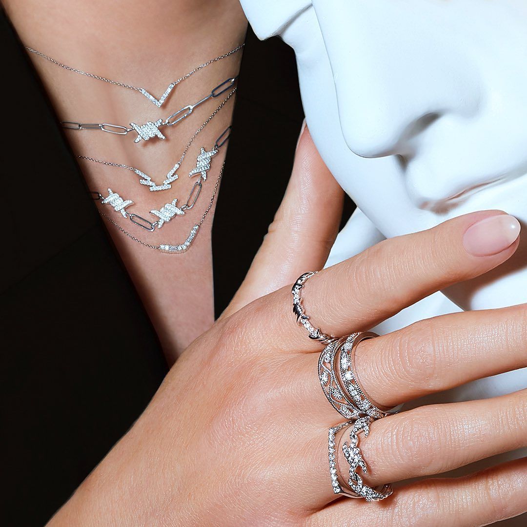 Main avec plusieurs bagues en diamant et bracelets superposés.