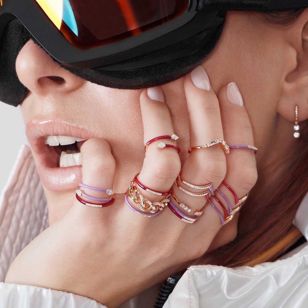 Femme portant plusieurs bagues aux doigts, bouche ouverte, portant des lunettes et des boucles d'oreilles.