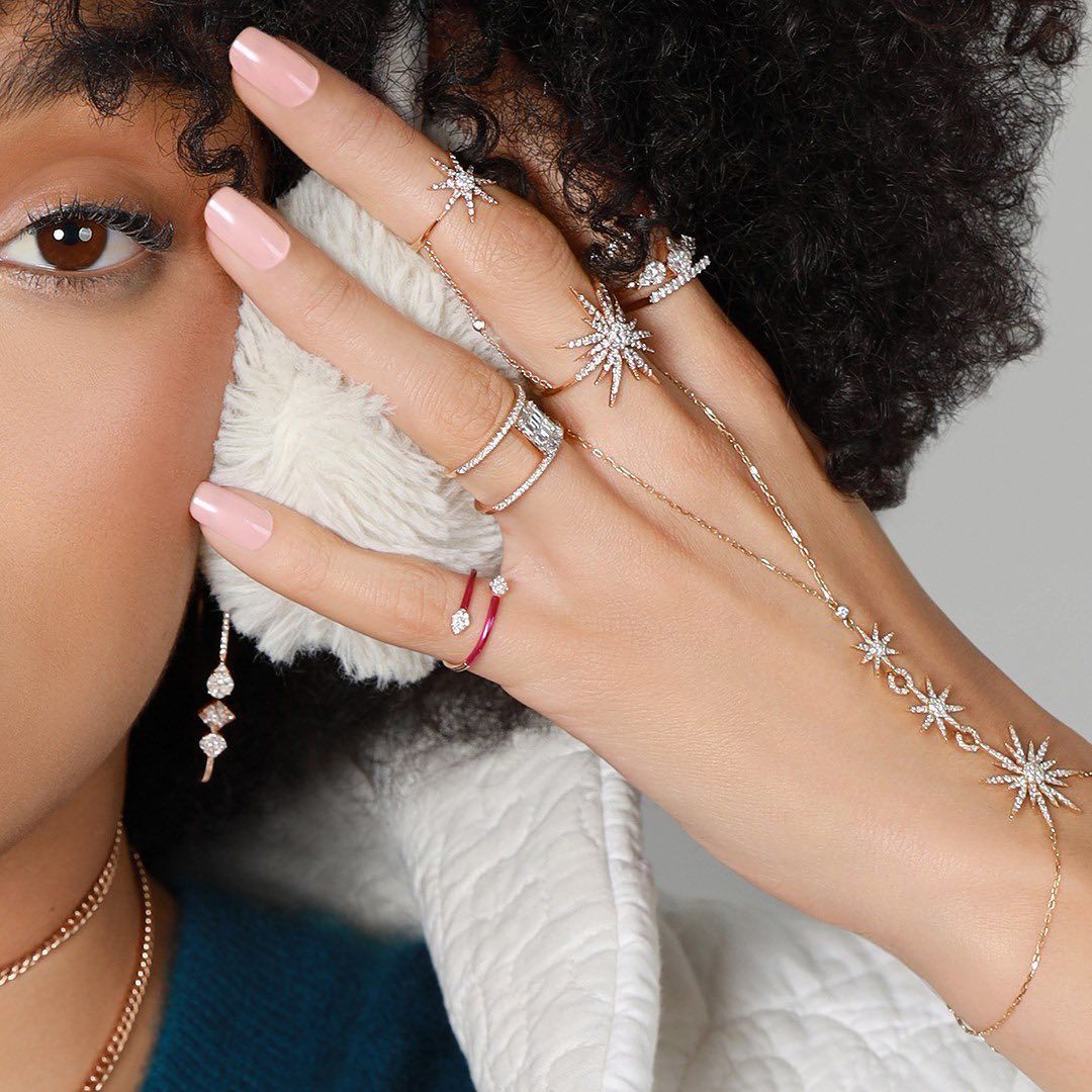 Main de femme ornée d'anneaux en forme d'étoile et d'une chaîne de main, oreille recouverte d'un cache-oreilles.