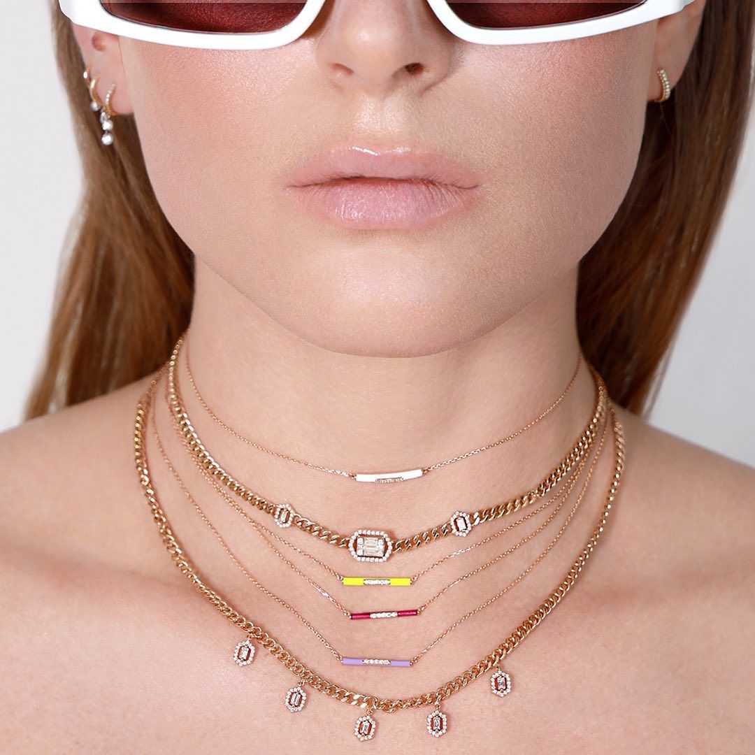 Femme portant plusieurs colliers en or avec des accents de diamants.