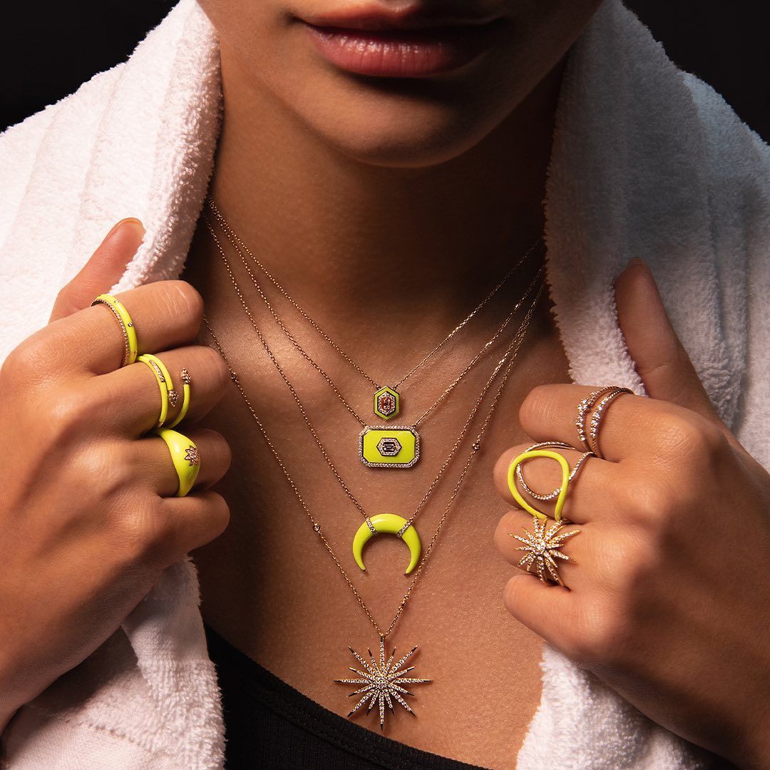 Femme portant plusieurs bijoux jaune fluo, tenant une serviette blanche.