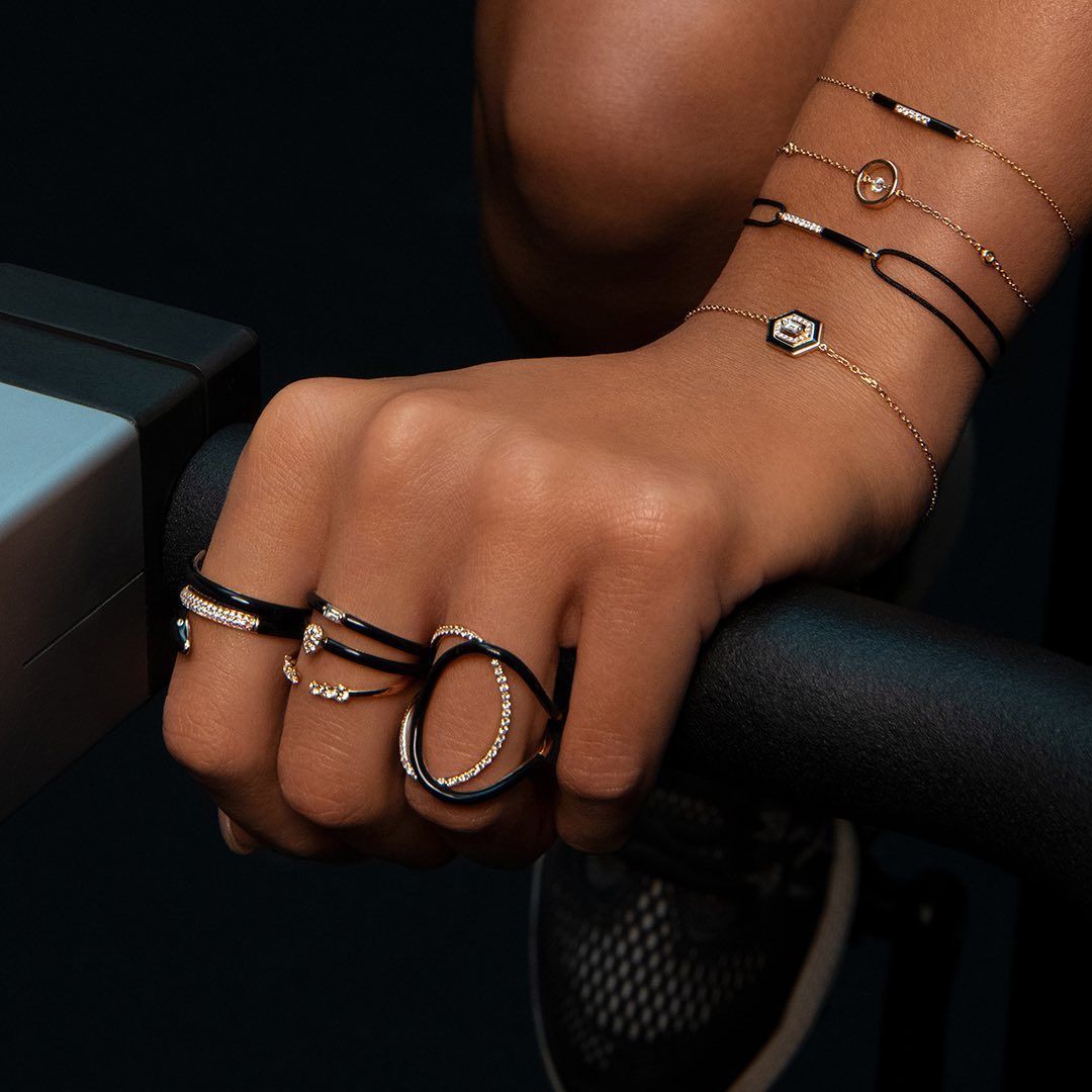 La main d'une personne portant des bijoux en or et en noir repose sur une machine d'entraînement.