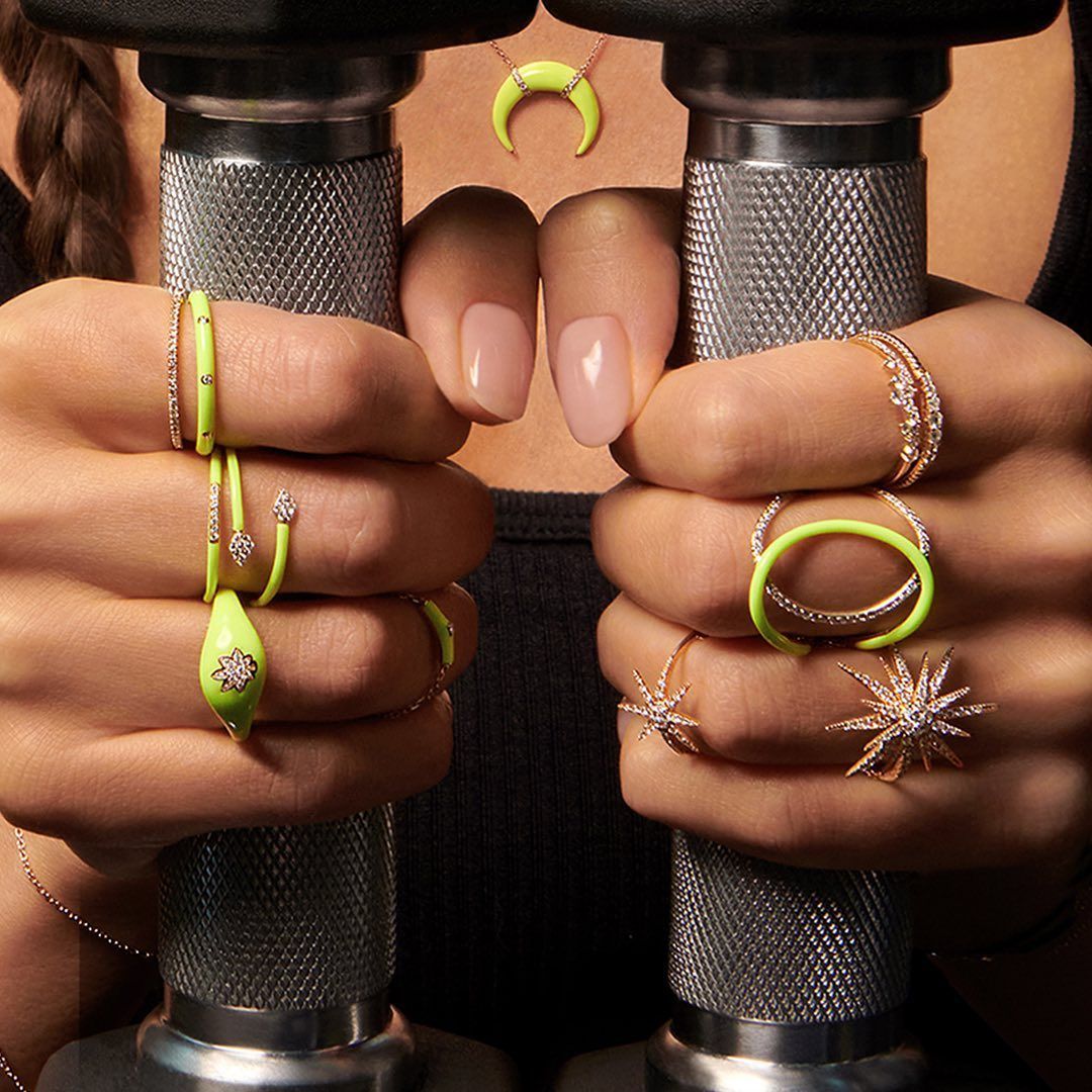 Personne tenant des haltères, portant diverses bagues et un collier jaune fluo.