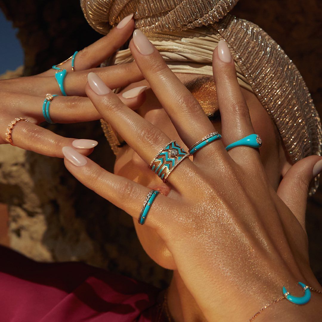 Mains ornées d'anneaux turquoise, coiffée d'un couvre-chef en or.
