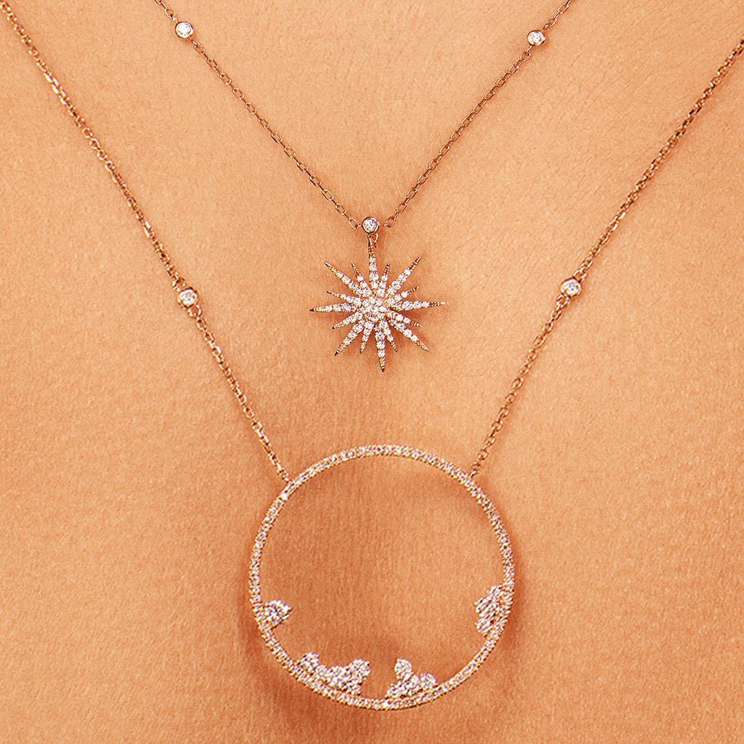 Colliers à trois pendentifs en diamant sur fond pêche. Motifs en étoile, en cercle et linéaires.