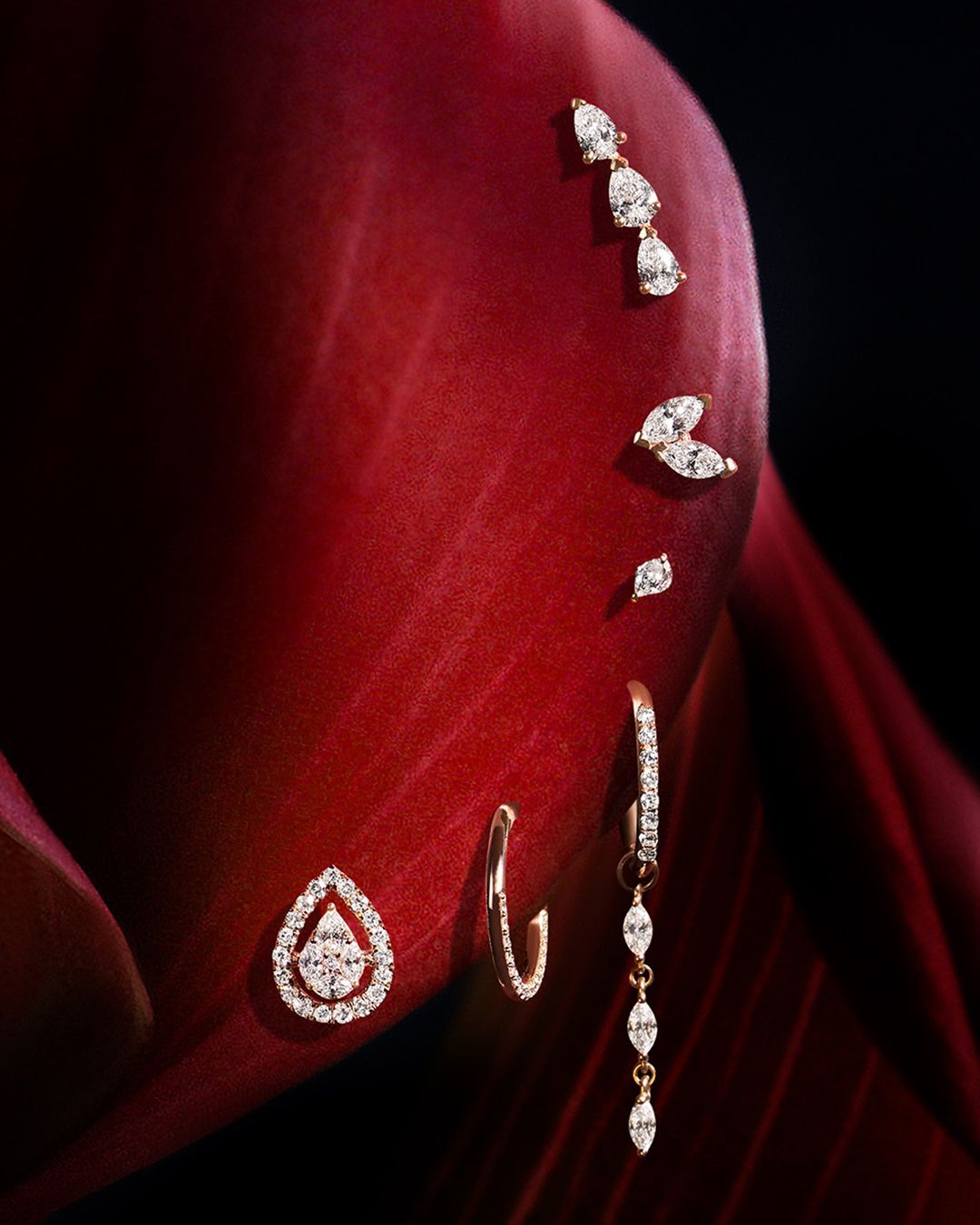 Boucles d'oreilles en diamant présentées sur un fond rouge en forme de pétale, dans des styles variés, de la larme au pendentif.