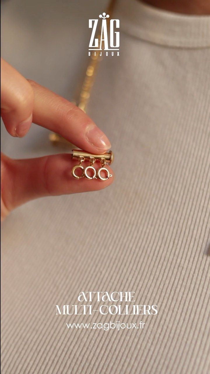 Une main tient une chaîne en or et un pendentif avec les initiales « CQG ». Texte : Attacher multicolore.