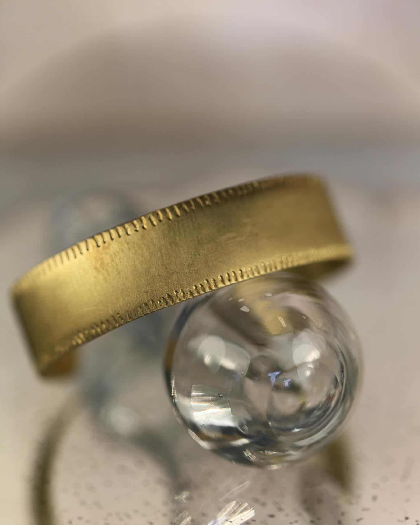 Bague en or reposant sur une sphère en verre transparent.