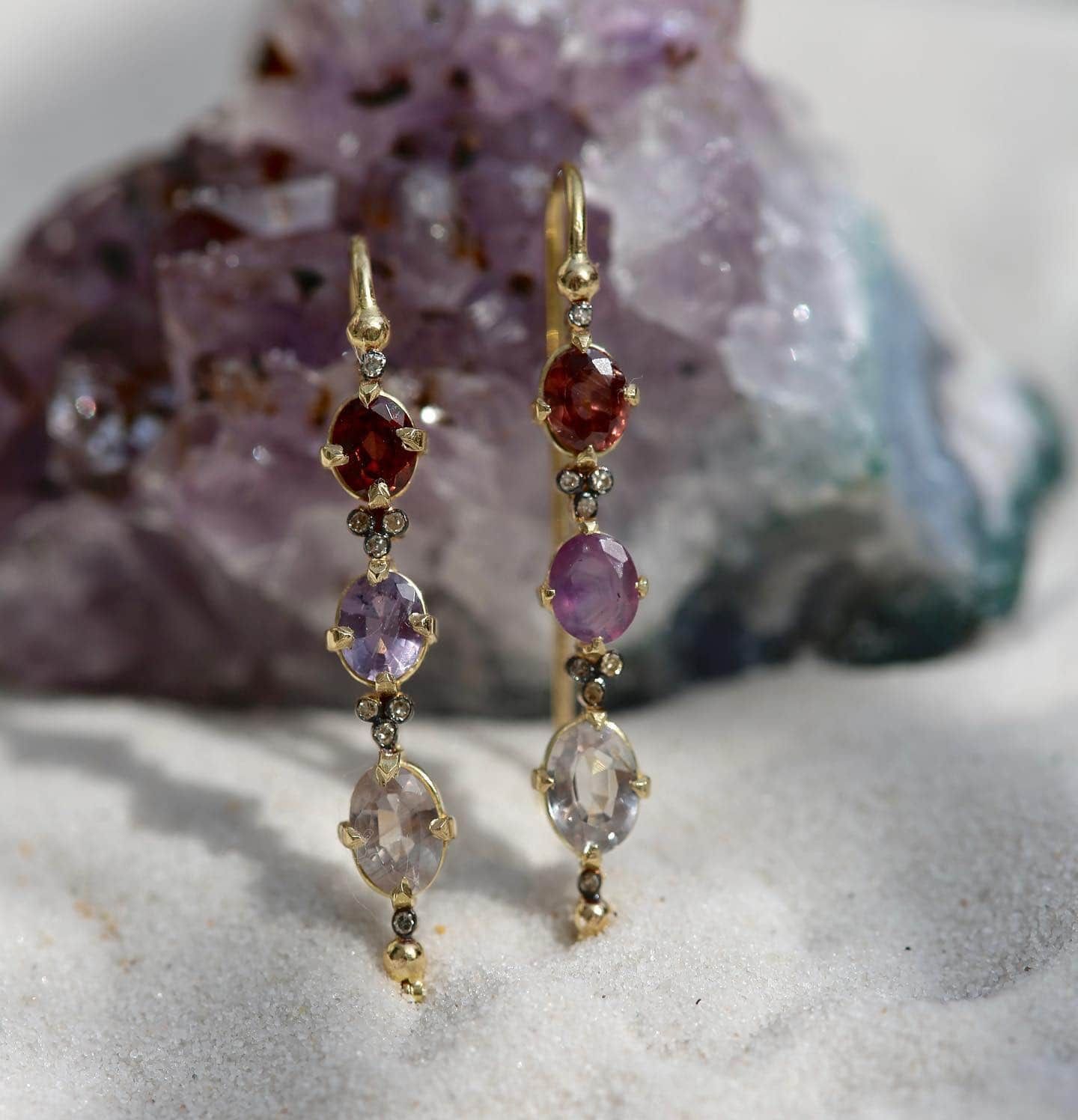 Boucles d'oreilles en or avec pierres précieuses rouges, violettes et transparentes, serties sur une géode d'améthyste.