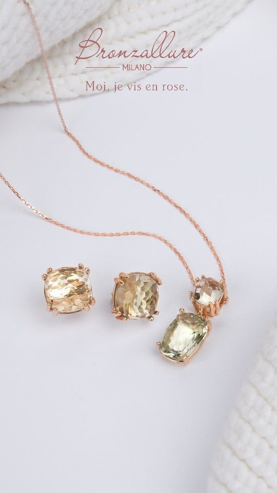 Parure de bijoux en or rose sur fond blanc : boucles d'oreilles et pendentif avec cristaux carrés jaune clair.