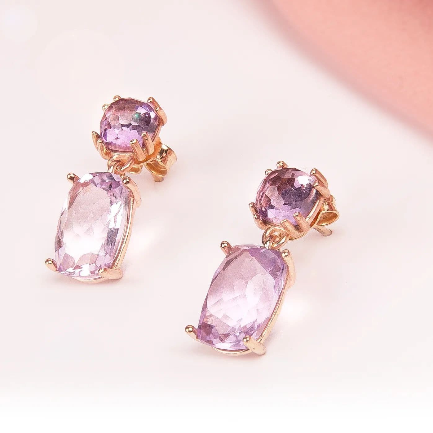 Boucles d'oreilles en or avec deux pierres précieuses violettes claires de taille ovale.