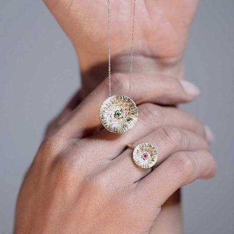 Parure de bijoux en or : collier et bague avec pendentifs circulaires texturés, ornés de pierres précieuses colorées.