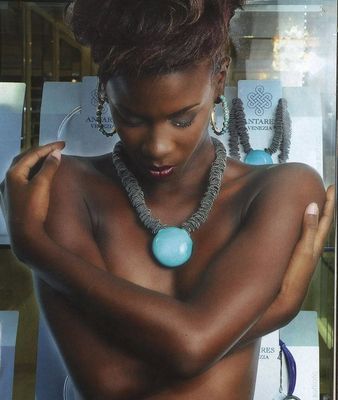 Femme portant un collier Antares, se serrant contre elle-même, devant une vitrine à bijoux de venus creation en Martinique