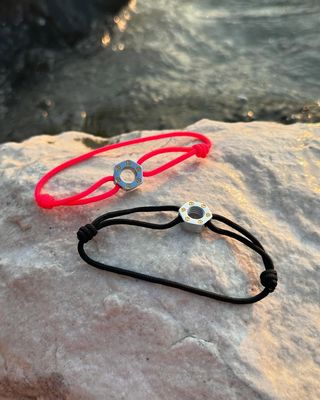 Une grande sculpture orange, blanche et noire encadre une vue sur une plage et le ciel.