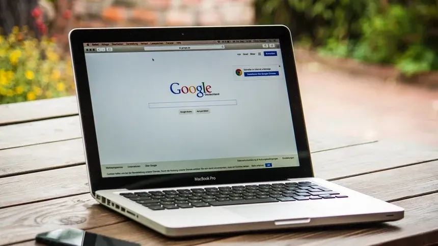 A laptop is open to a google page on a wooden table.