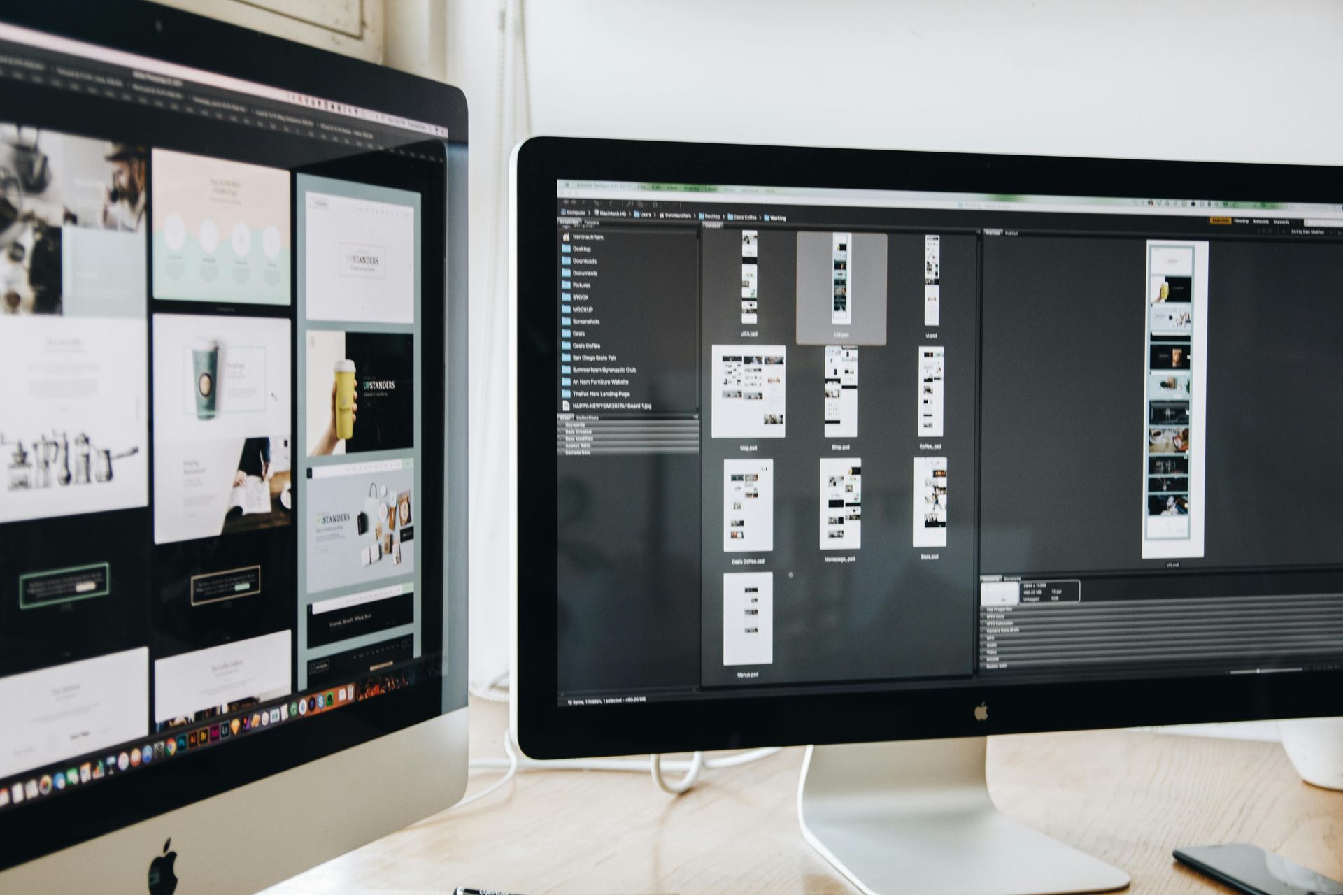 Two computer monitors are sitting next to each other on a desk showing web design.
