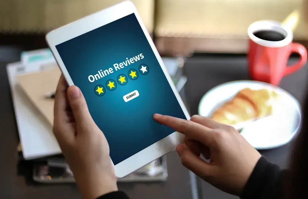 A person is holding a tablet with online reviews on it.