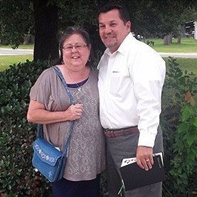 Cathy and John Andrews pose next to each other outdoors.