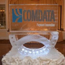Clear acrylic display with COMDATA Payment Innovation logo on a table with glowing lights below