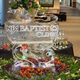 Ice sculpture display at a floral event with the words “NEA Baptist Clinic” engraved on it.