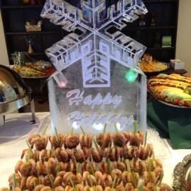 Festive dessert table with snowflake centerpiece, “Happy Holidays” sign, and rows of chocolate-covered treats