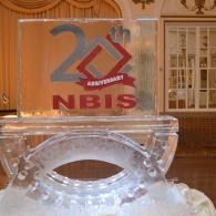 Transparent acrylic 25th anniversary NBIS award with blue and red lettering on a decorative table