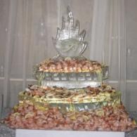 Food display ice sculpture covered with shrimp and topped with a sculptured shaped centerpiece