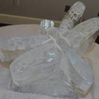Transparent ice sculpted figurine of a dragonfly on a white surface