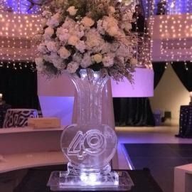 Floral centerpiece on a lit acrylic base with “40” at a decorated event table