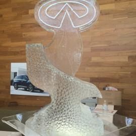 Transparent ice sculptured logo centerpiece with a wooden wall backdrop