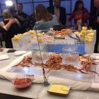 Seafood buffet table with crab legs, shrimp, lemon wedges, and guests standing in the background