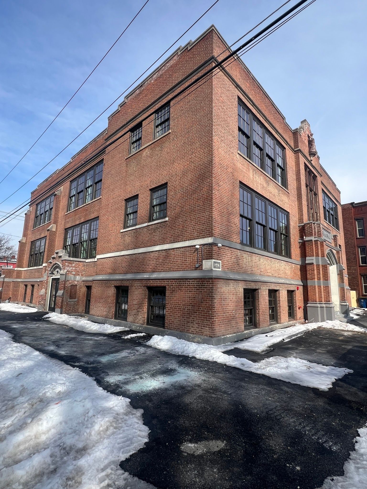Brick building with large windows and snow-covered ground.