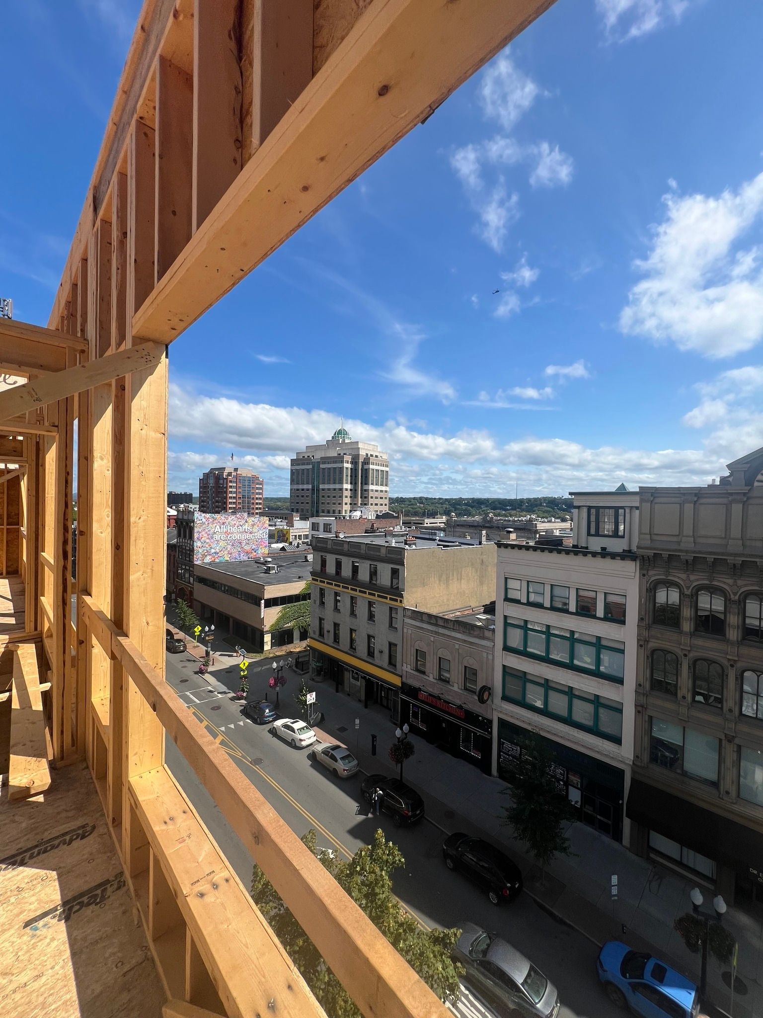 Wooden construction frame overlooking a city street on a sunny day.