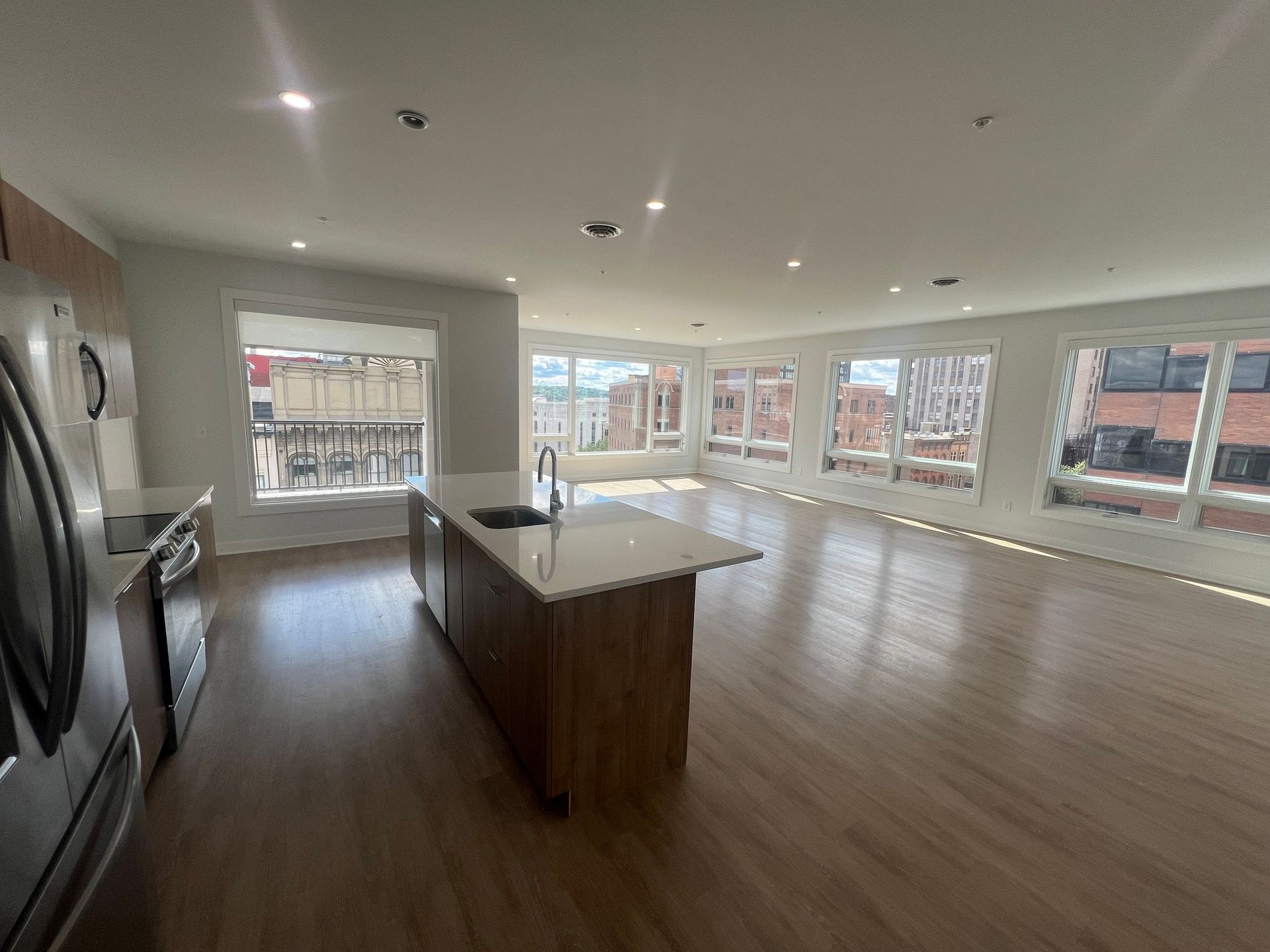 Spacious open-concept kitchen and living area with island, large windows, and hardwood floors.