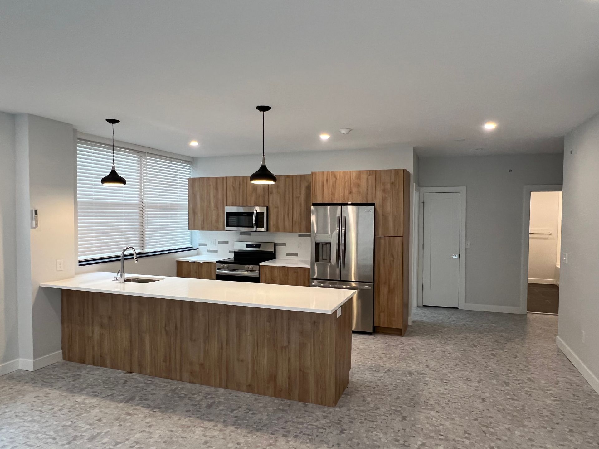 Modern kitchen with wood cabinets, island, and stainless steel appliances.