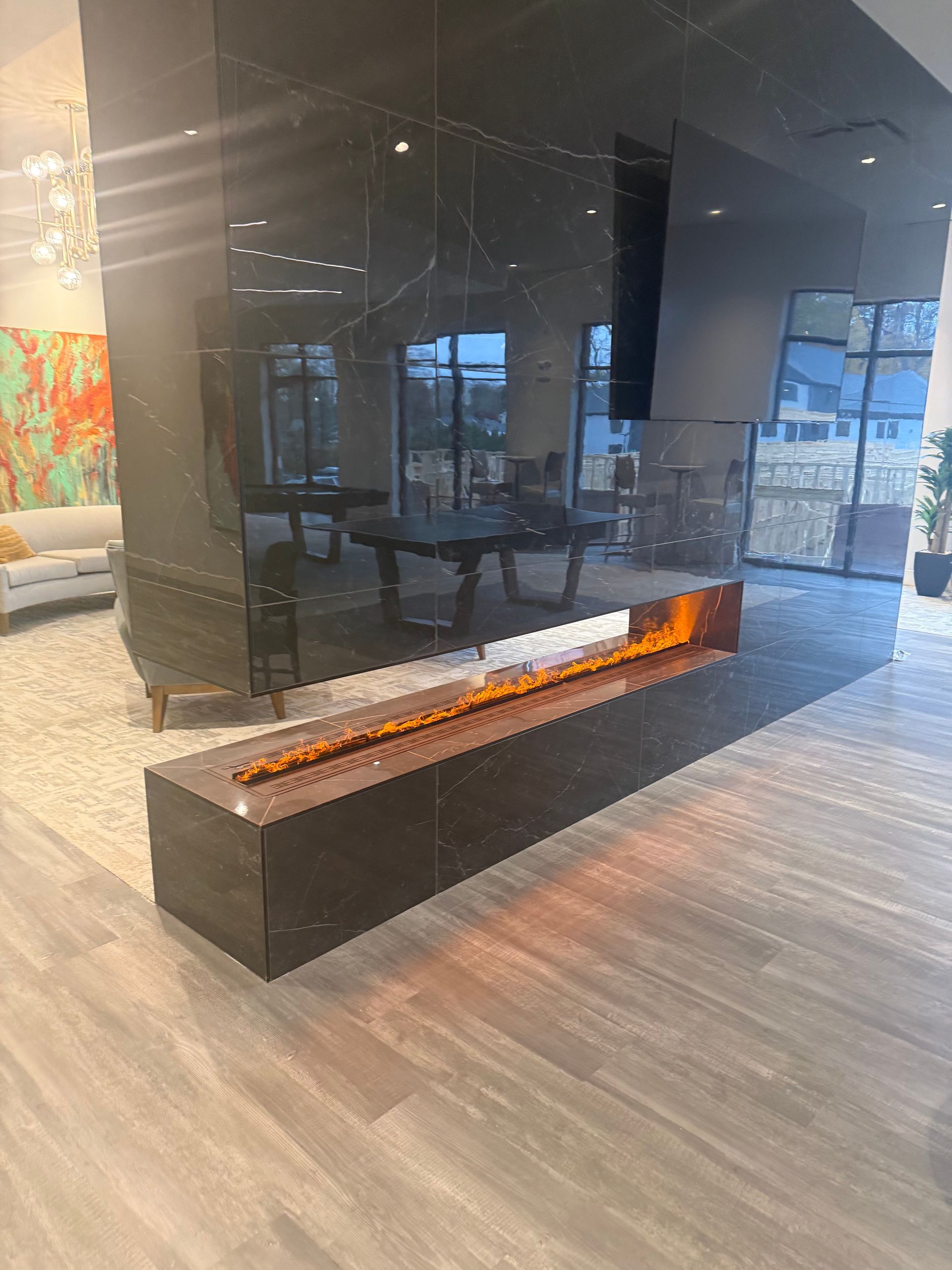 Modern fireplace with long flames against a dark, stone wall in a showroom.