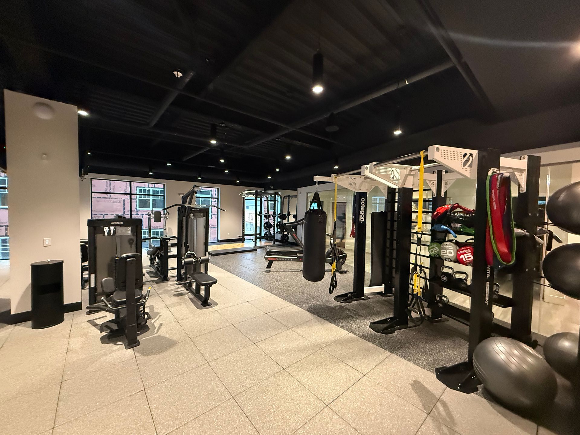 Gym with various exercise machines, punching bag, and free weights, indoors.