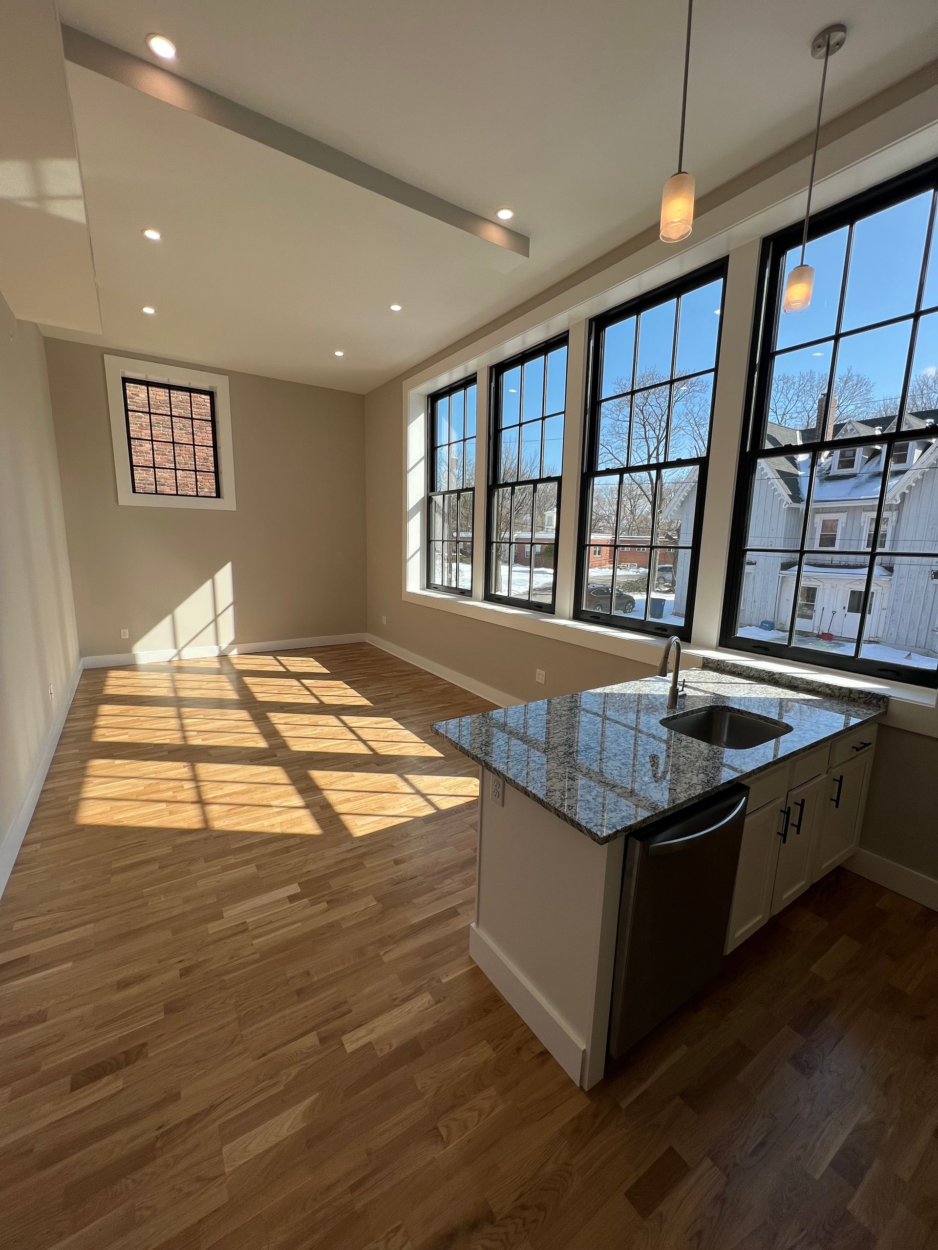 Bright kitchen area with island, windows, and hardwood floors.