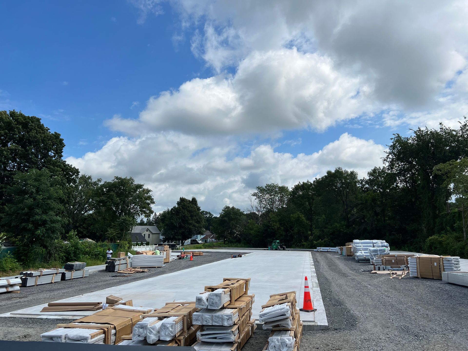 Construction site with concrete foundation, materials, and blue sky with clouds.