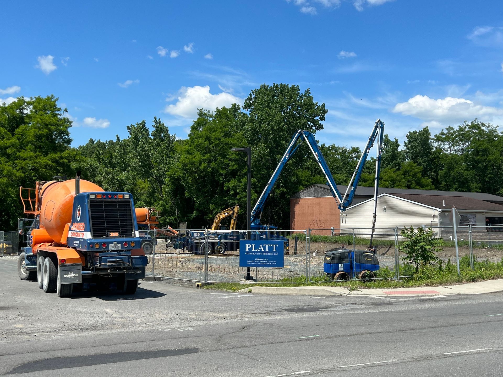 Construction site with concrete mixer truck and machinery; building demolition in progress.