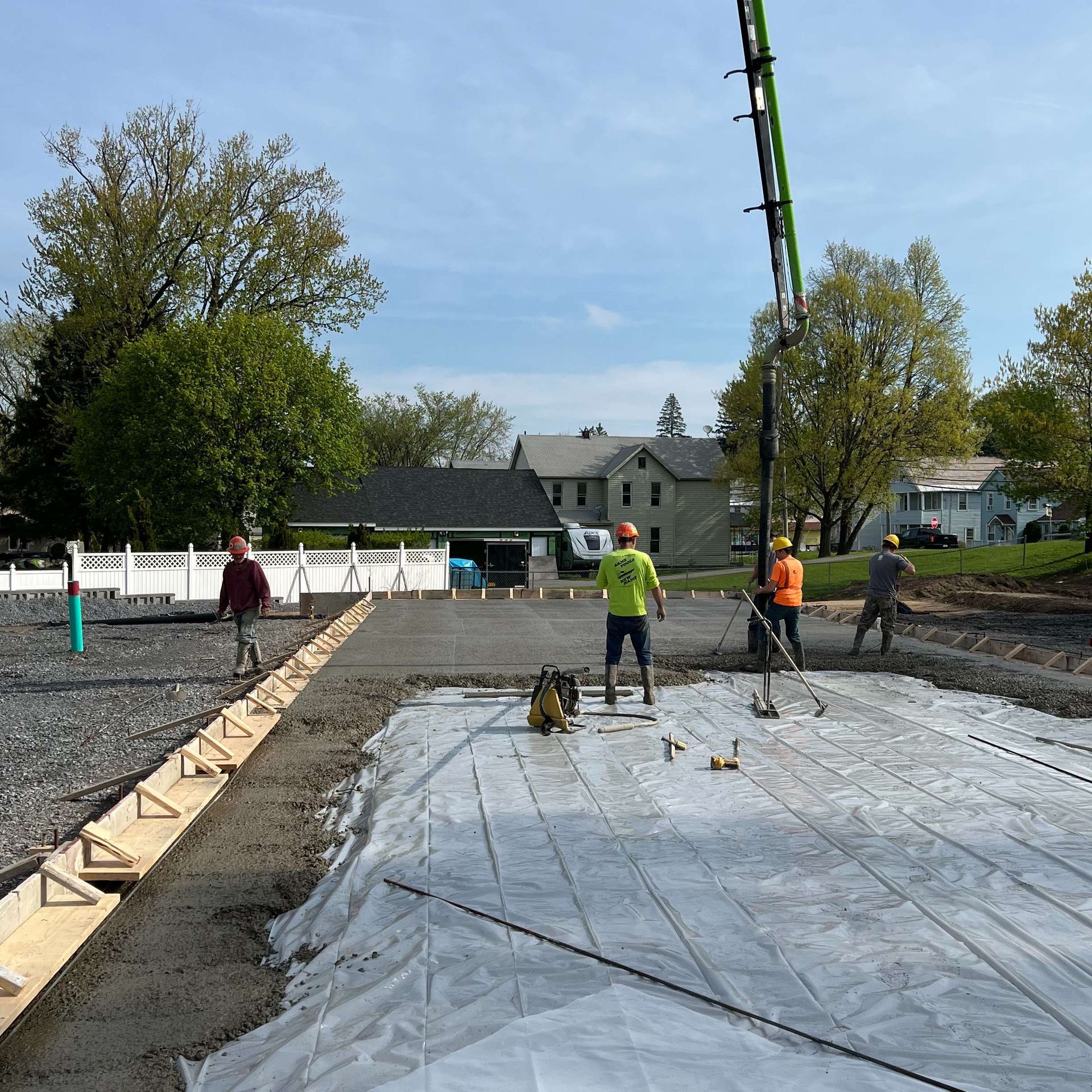 Construction site with workers pouring concrete using a pump truck; bright sunny day.
